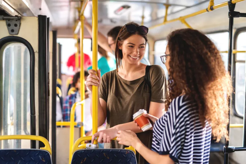 happy multicultural teenage girls chatting and standing in the city bus