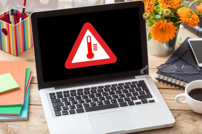 high temperature warning sign on a laptop screen computer overheating concept heavy load and hot weather danger business office desk background