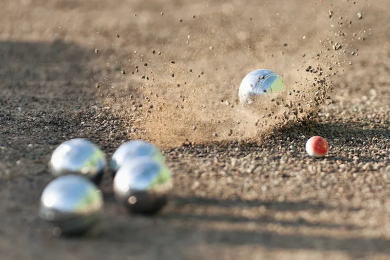 petanque ball boules bowls on a dust floor, photo in impact game of petanque on the ground balls and a small wood jack