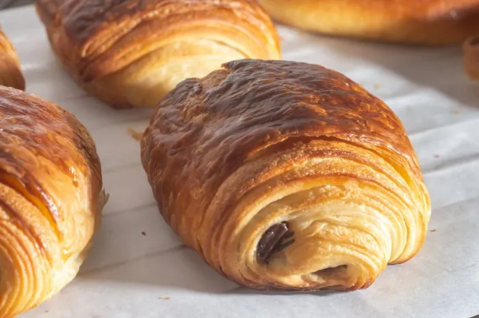 freshly backed french traditional croissant chocolate - petit pain au chocolat shiny in the rays of the morning sun