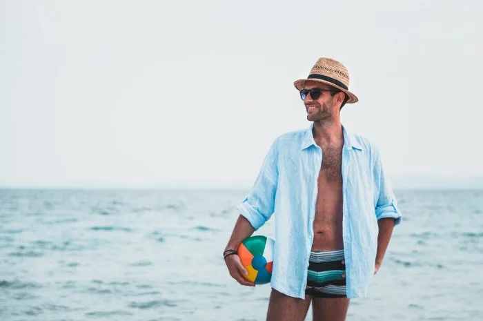 young man holding ball at the beach