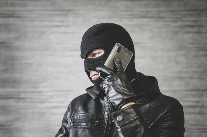 robber making phone gesture the concept of telephone terrorism and fraud a masked man makes a phone call
