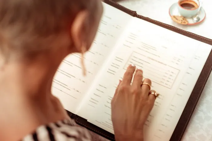 reading the menu top view of woman wearing nice rings reading the menu in restaurant sitting at summer terrace