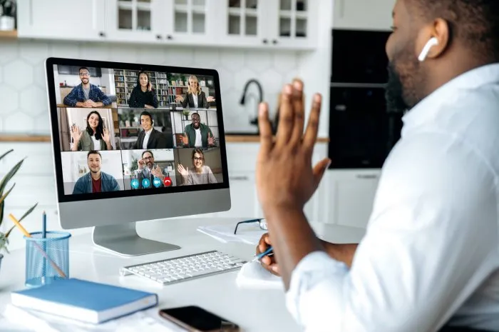 video call, online conference over shoulder view of african american man at computer screen with multinational group of successful business people, virtual business meeting, work from home concept