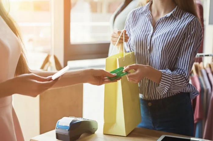 woman paying with credit card for purchase at clothes showroom finance and non-cash transaction concept