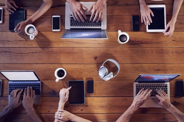 overhead shot of young adults using technology at a table