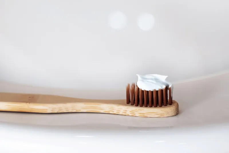 wooden eco toothbrush with toothpaste bamboo toothbrush on a white sink washbasin background