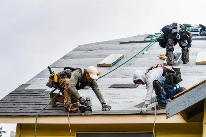 everett wa usa - 03-23-2021  crew installing new shingles on roof on a rainy day