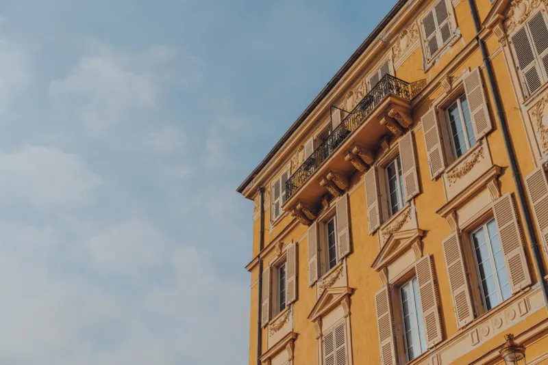 low angle view of traditional colourful building with wooden window shutters in the old town of nice, france, against blue sky