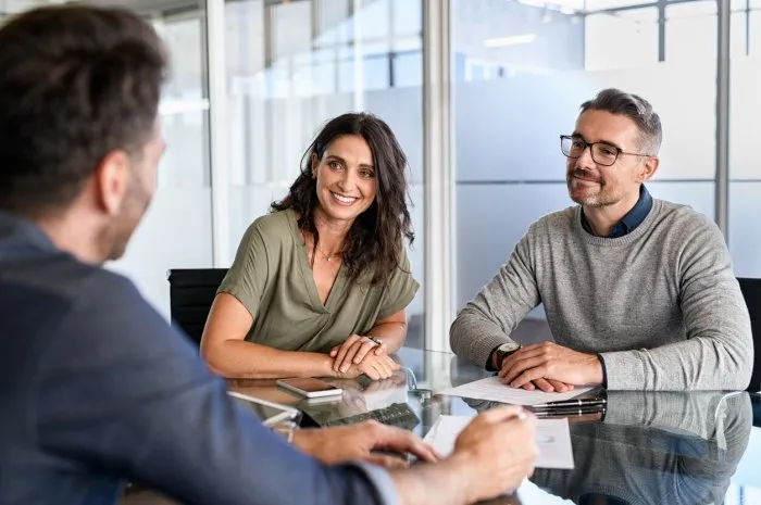 smiling mature couple meeting with bank manager for investment beautiful mid adult woman with husband listening to businessman during meeting in conference room in modern office happy middle aged couple meeting loan advisor to buy a new home