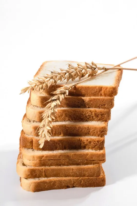 sliced wheat bread and wheat on a white background