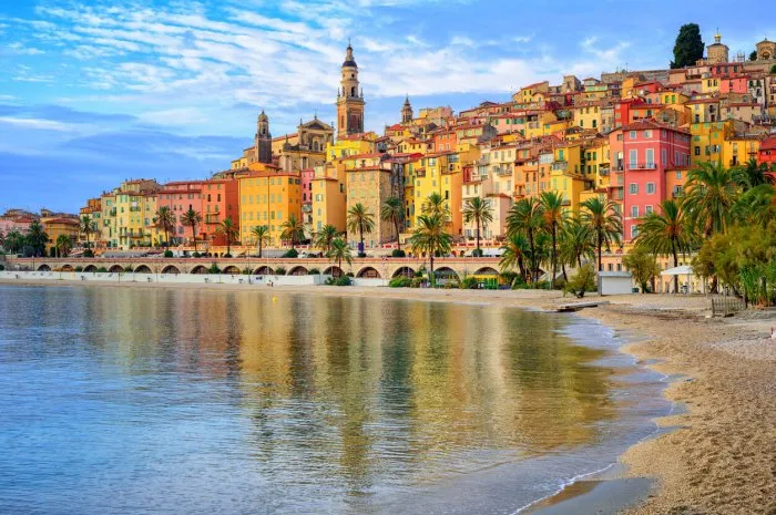sand beach beneath the colorful old town menton on french riviera, france