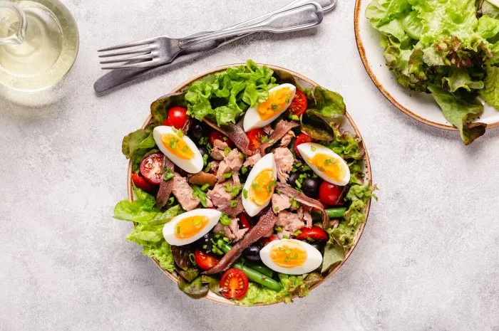 french salad nicoise with tuna, eggs, green beans, tomatoes, olives, lettuce and anchovies