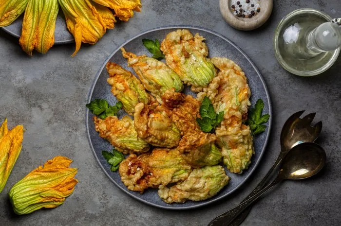 fried in a batter zucchini flowers stuffed with ricotta cheese and parsley raw and roasted courgette or pumpkin flowers italian dish fiori di zucca in pastella gray background