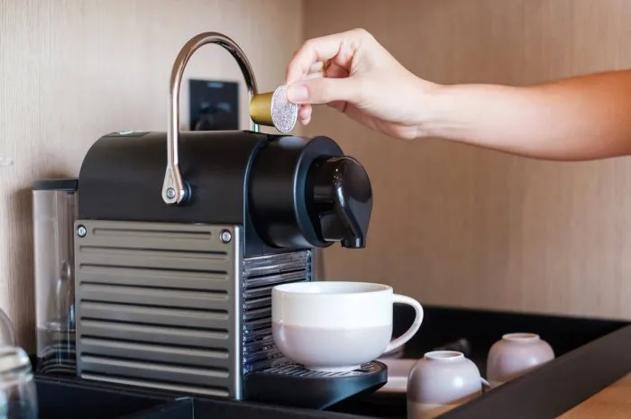 hand making espresso by coffee machine with capsules on wood table