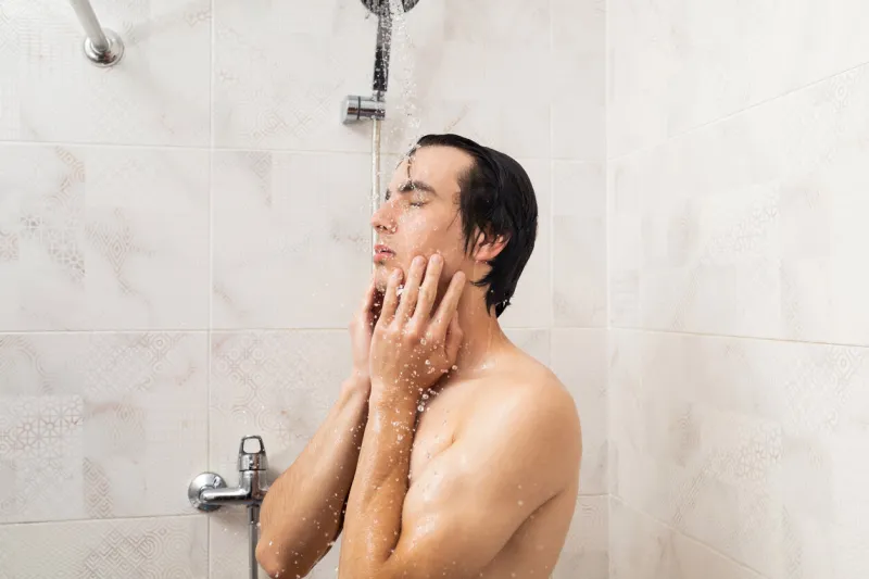 a man is taking a shower drops of water falling on him from the shower head