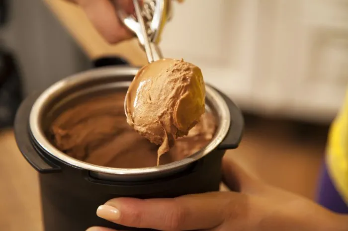 unrecognizable woman scooping and serving chocolate ice cream