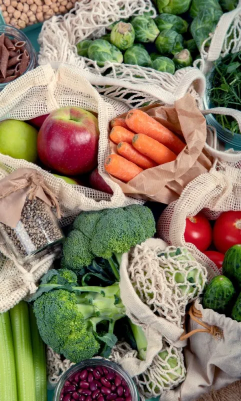 various organic fruits and vegetables in reusable packaging bags eco friendly lifestyle concept plastic free items reuse, reduce, refuse top view