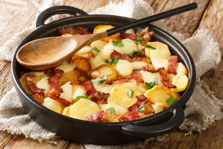 truffade is a rural dish itt is a sort of thick pancake made with thinly sliced potatoes and tome fraîche cheese close up in the pan on the table horizontal