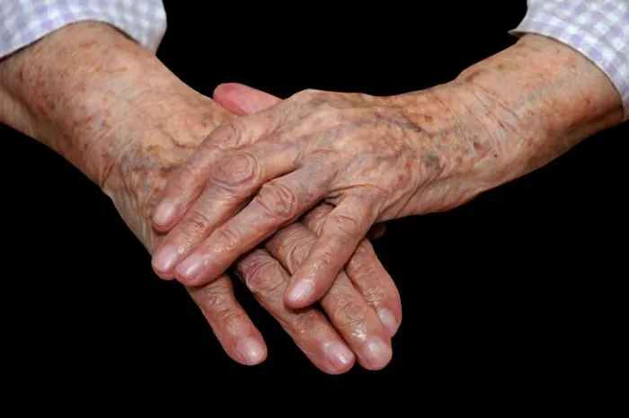 hands of a 103 years old lady on a black background