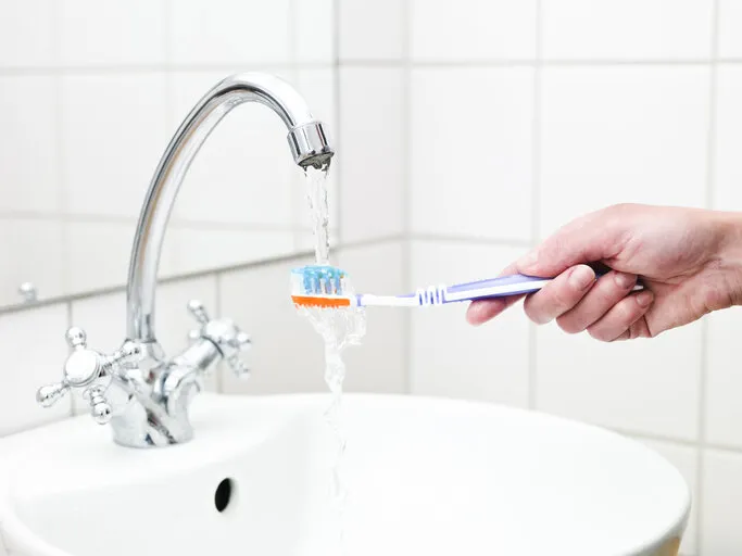 human holding toothbrush in water