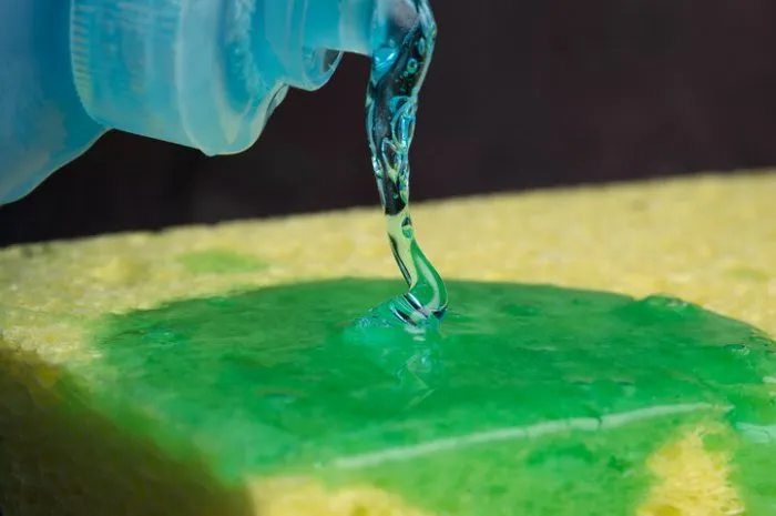 pouring liquid dish soap on a sponge