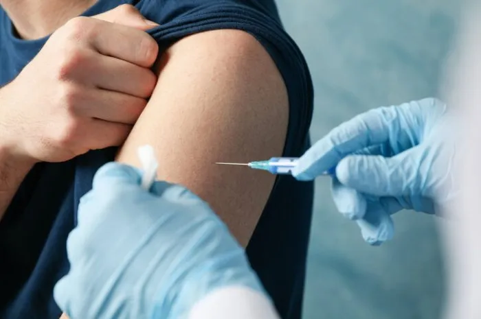 doctor does an injection patient on blue background coronavirus protection healthcare and medical concept