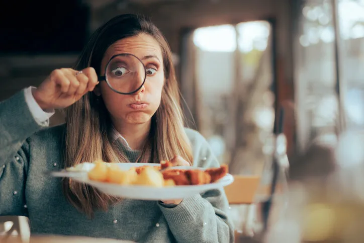 funny food critic checking the restaurant dish with a magnifying glass
