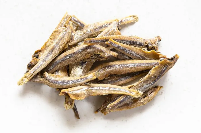 handful of dried anchovy fishes close up on gray plate