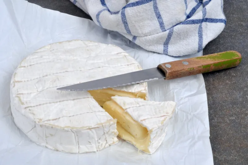 flowing camembert started with a knife in its open packaging