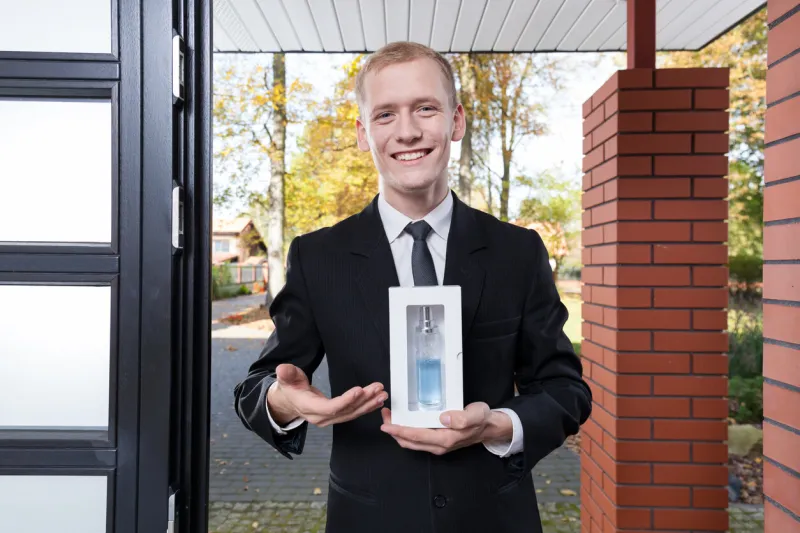 smiling salesman standing at the door and selling perfume