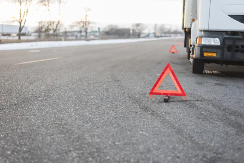 several bright red emergency triangles placed down road by truck parked to the side