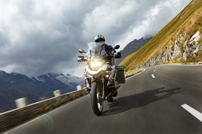 motorbiker riding in austrian alps, dramatic sky travel and freedom, outdoor activities