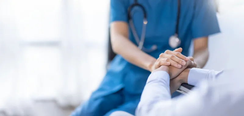 cropped shot of a female nurse hold her senior patient's hand giving support doctor helping old patient with alzheimer's disease female carer holding hands of senior man