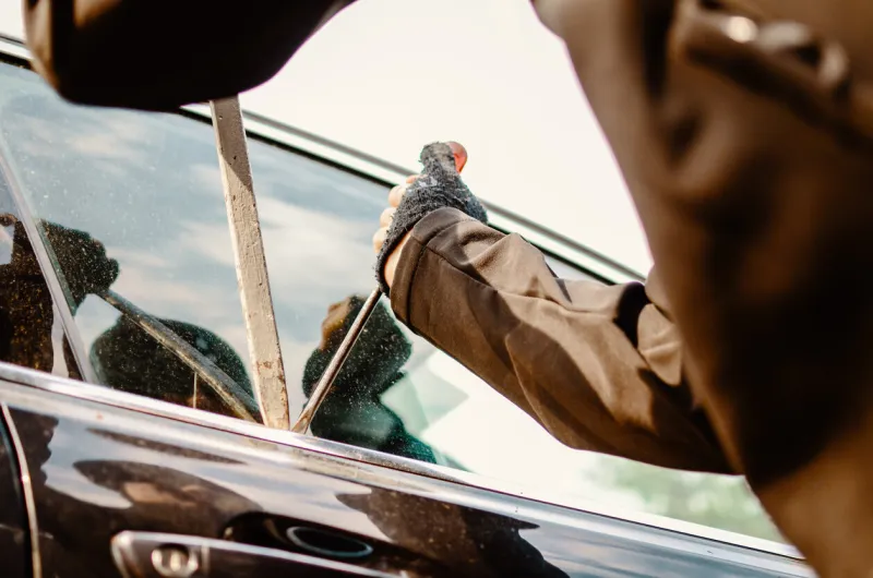 man thief robbing a car on parking bandit burglar in criminal scene opening and braking car window on force close up view copy space