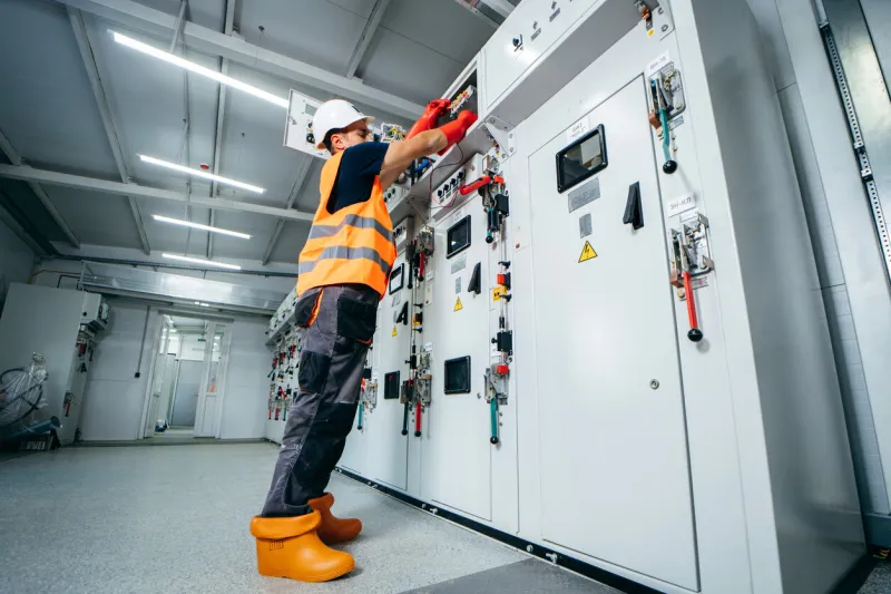 adult electrician builder engineer testing and screwing equipment in fuse box and repairing of modern electricity power station using voltmeter automatic control cabinet