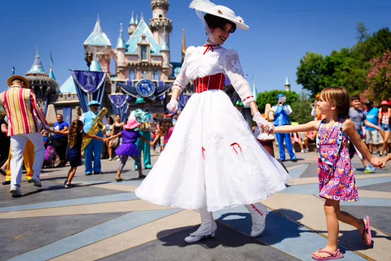 anaheim, ca - august 10th 2016  mary poppins smiles at a young child as she leads a line of children in song and dance in front of cinderella's castle during disney's 60th diamond celebration