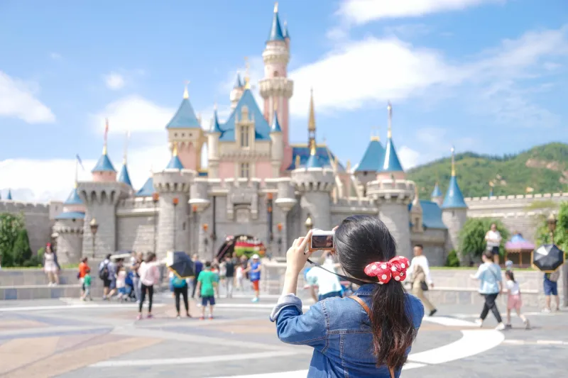 hong kong, china - oct 4, 2016  unidentified asian teenage girl with a ponytail hairstyle is taking photo of the fairytales sleeping beauty castle, at disneyland hong kong editorial used only