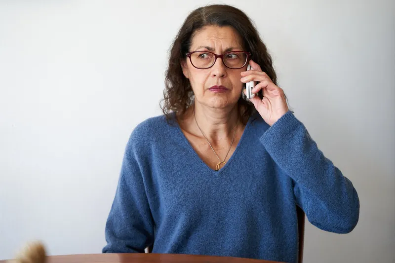 senior phone fraud concept mature woman distrusting phone call