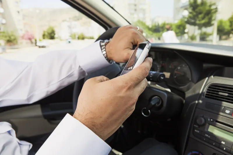 writing a message with his phone while driving