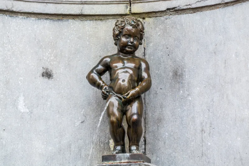 manneken pis, a landmark 61 cm (24 in) bronze sculpture in the centre of brussels (belgium), depicting a naked little boy urinating into a fountain's basin