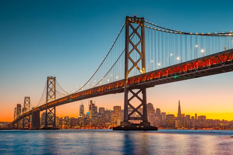classic panoramic view of san francisco skyline with famous oakland bay bridge illuminated in beautiful golden evening light at sunset in summer, san francisco bay area, california, usa