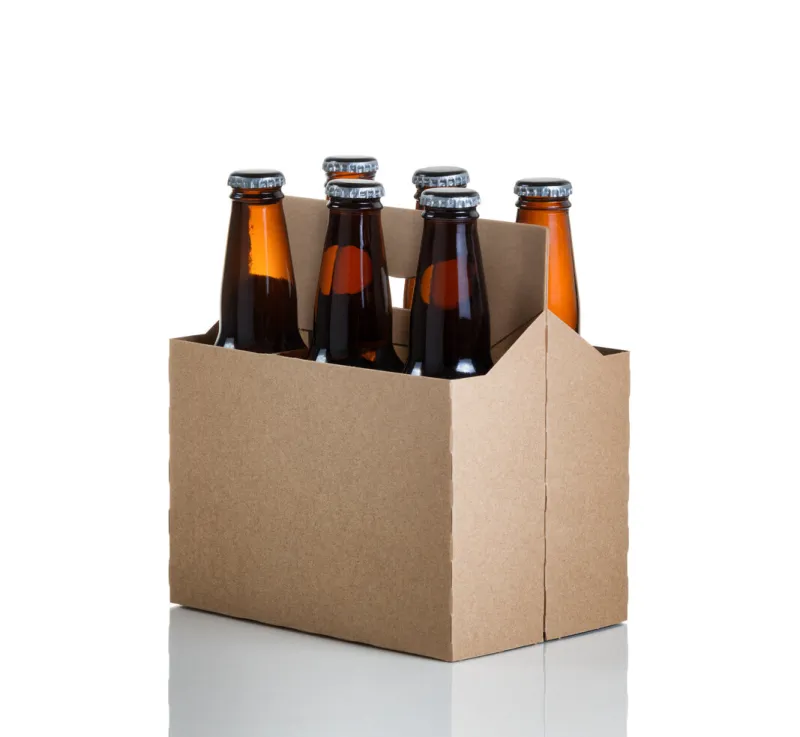 angled view of a six pack of glass bottled beer in generic brown cardboard carrier isolated on white with reflection