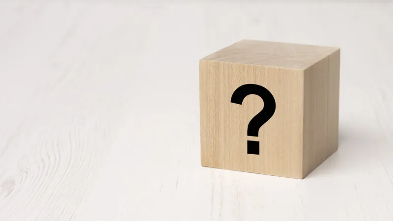 wooden block with black question mark on white wooden table background, business teamwork concept