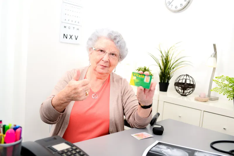senior woman in doctor's office showing carte vitale medical french social security card