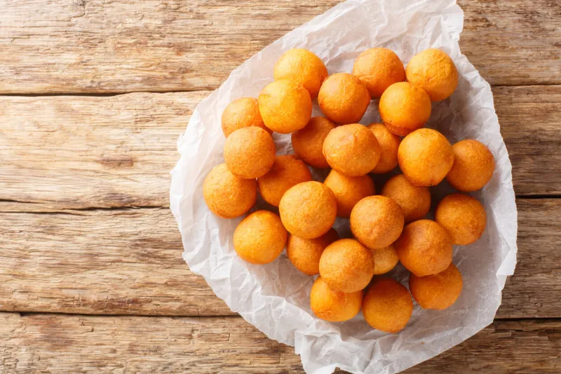 quail egg-shaped fried sweet potato balls deep fried in oil closeup on the wooden table horizontal top view from above