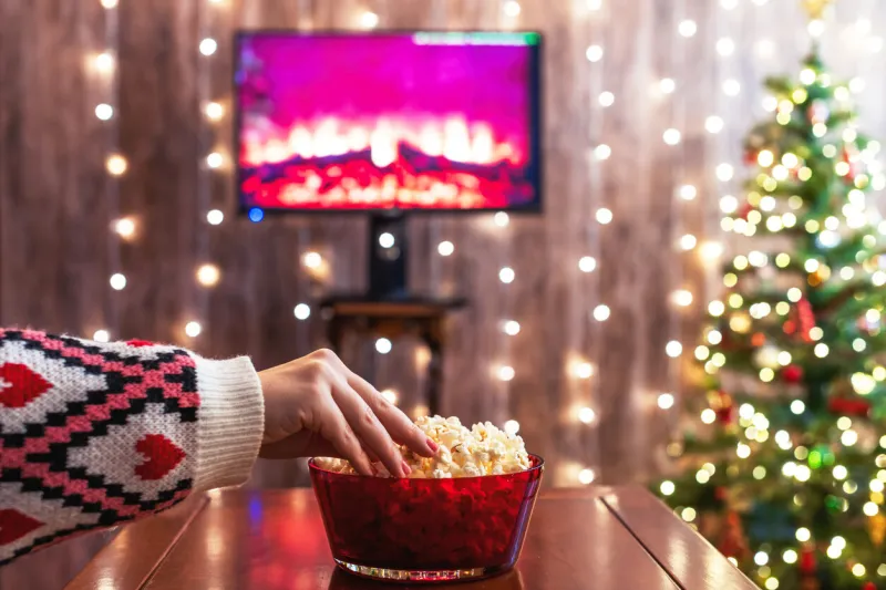 christmas eve alone woman watching tv and eating popcorn home cinema cropped, close up