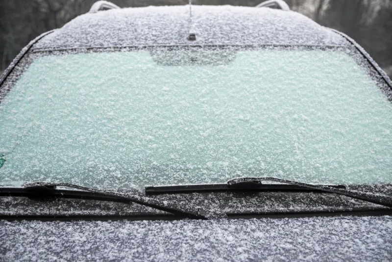 frozen windshield of a car with ice and snow, concept of traffic risks in winter, copy space, selected focus