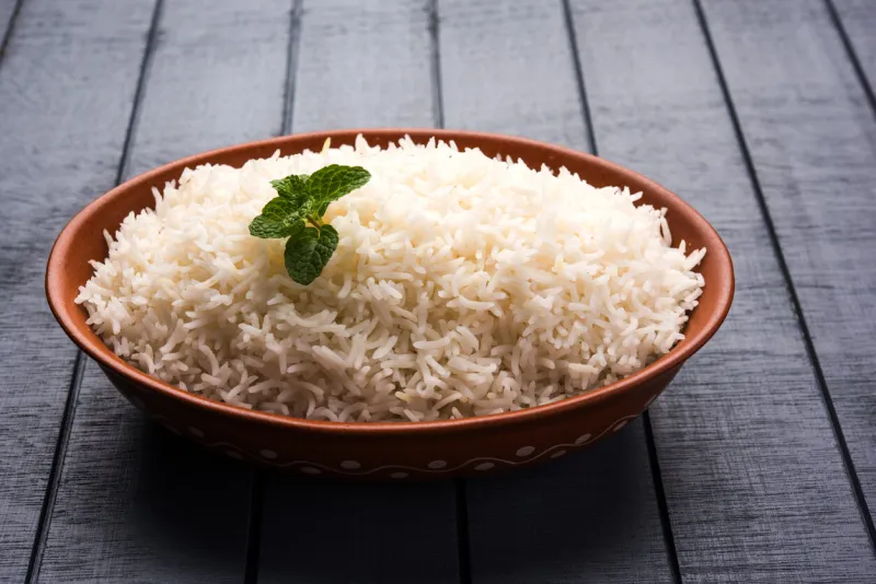 cooked plain white basmati rice in terracotta bowl over plain or wooden background