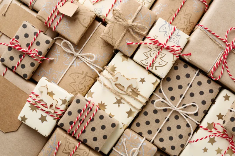 christmas background with many decorative homemade gift boxes wrapped in brown kraft paper red white twine flat lay
